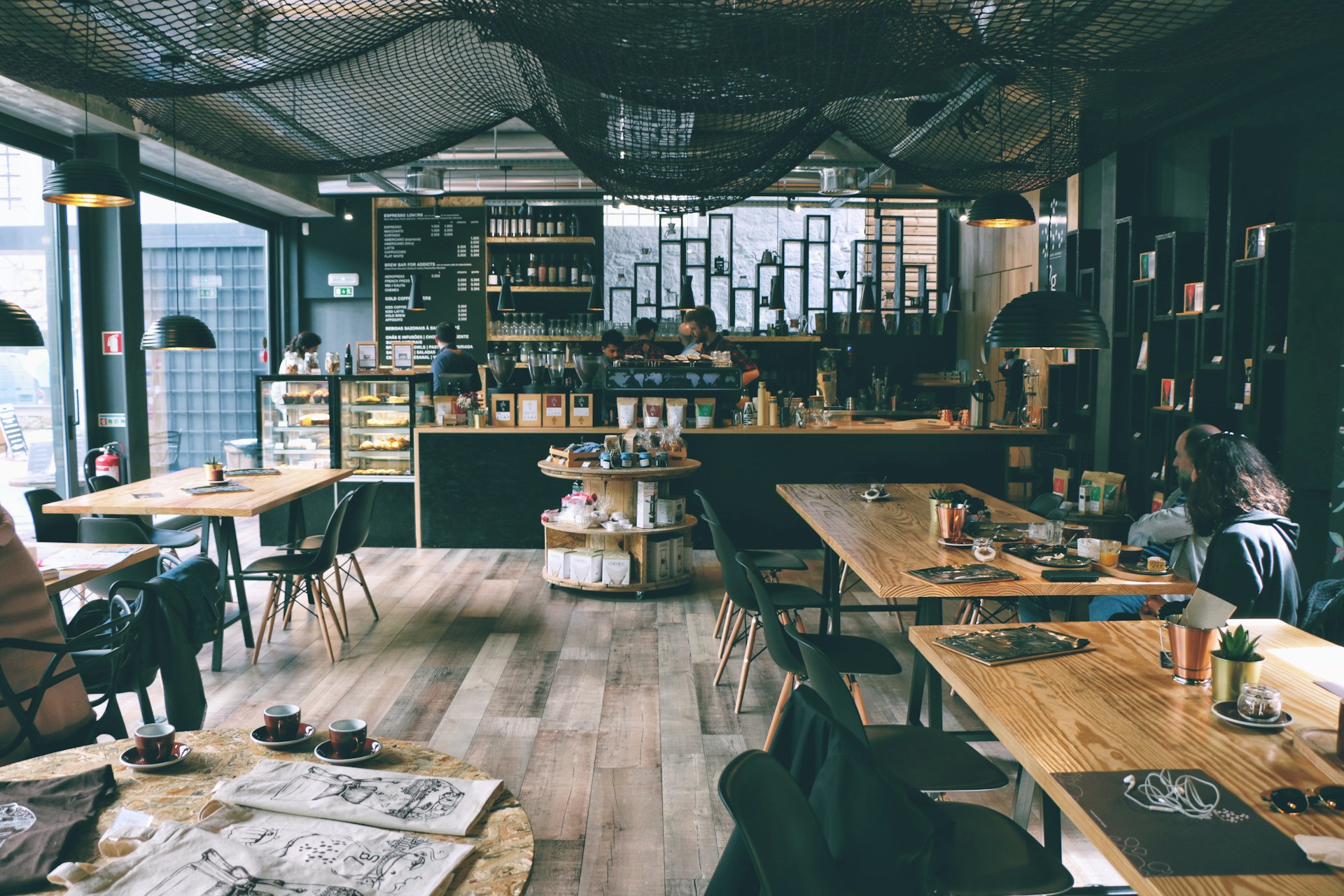 A warmly lit restaurant and cafe interior with wooden tables and an open kitchen counter
