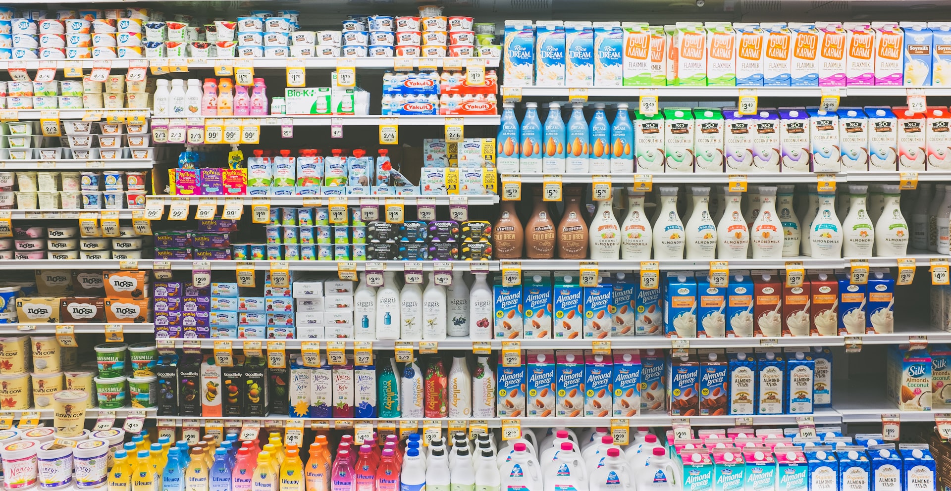 A refrigerated supermarket dairy aisle stocked with packaged goods