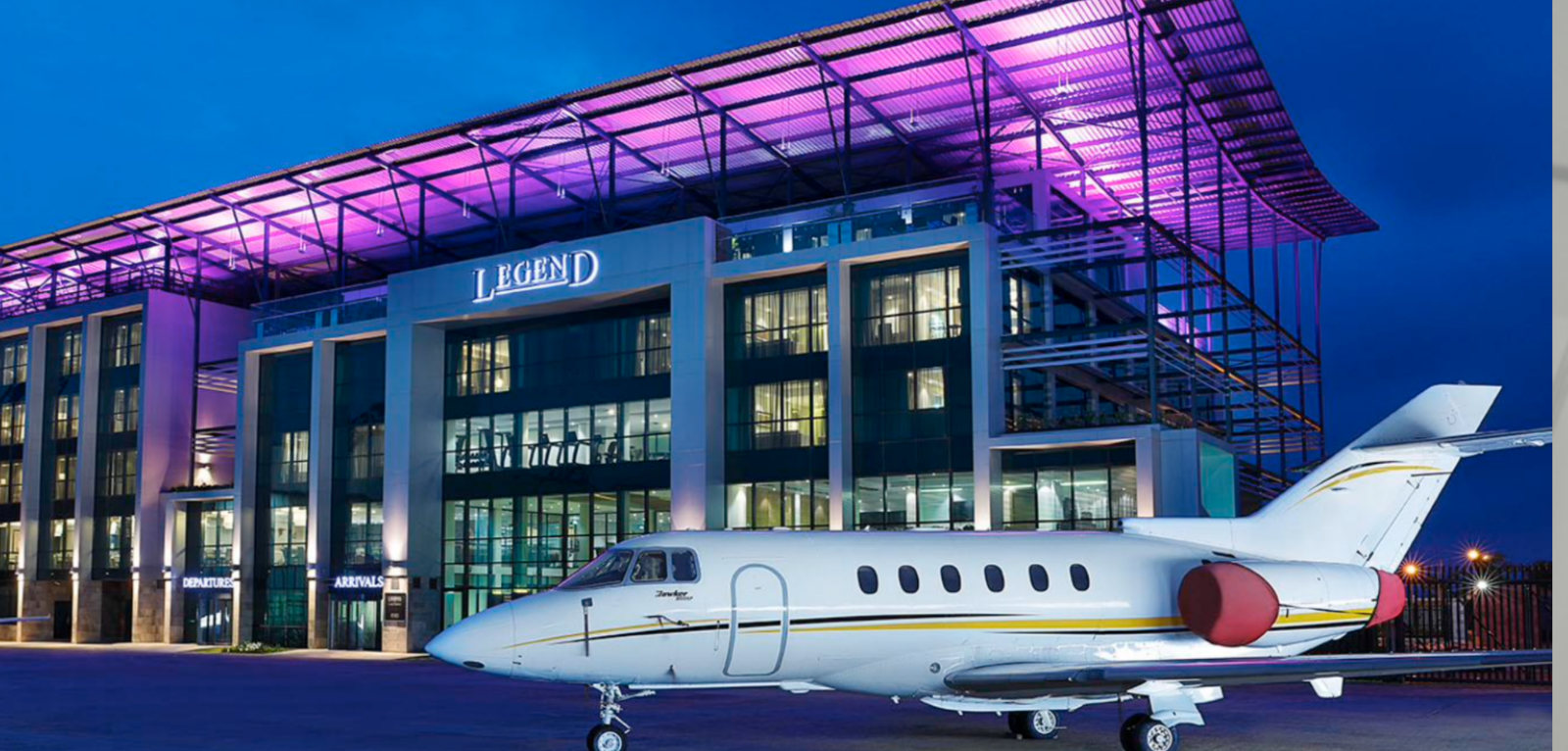 A private jet parked before the illuminated Quits Aviation private terminal in Lagos at dusk